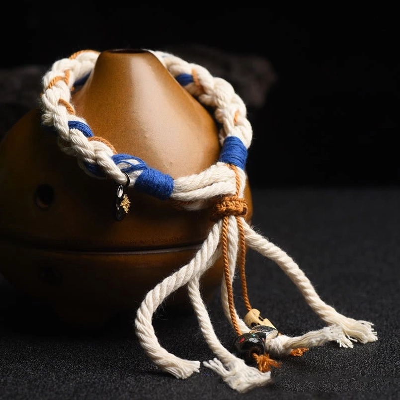 Close-up side view of Zakiram bracelet showing navy blue binding sections and tassel details on brown ceramic ornament