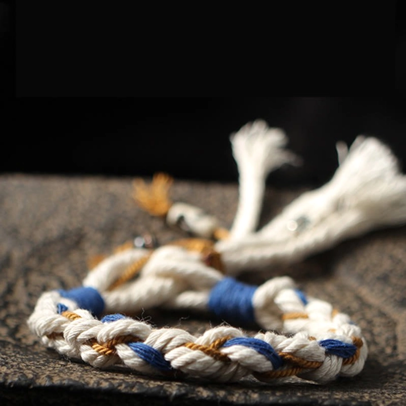Detail close-up of Zakiram bracelet showing brown knot, white cotton tassels and metal ceramic pendants