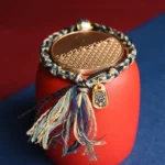 Handmade Zakiram Goddess red string bracelet with copper beads and metal charm, blue and multicolor design