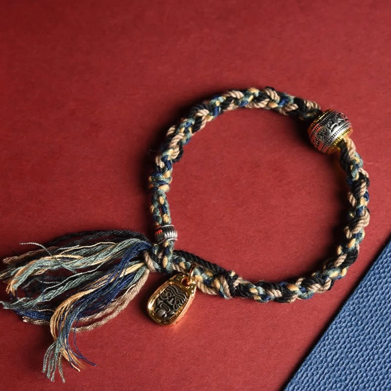 Tibetan Om Mani Padme Hum bracelet flat lay showing intricate braided cotton cord and vintage metal pendant