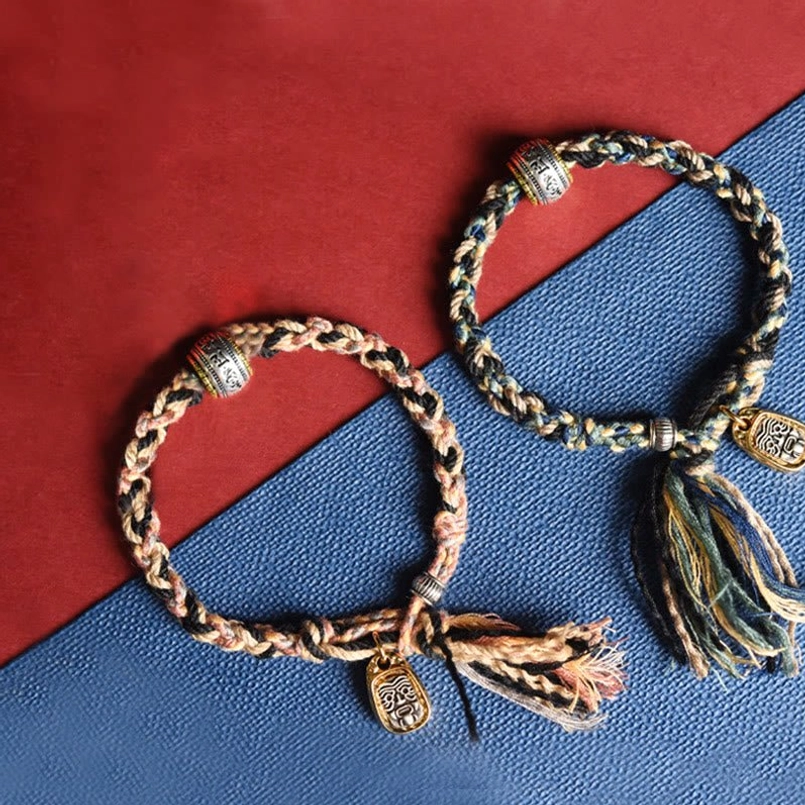Multiple Zakiram Om Mani Padme Hum bracelets in brown and light beige with copper pendants