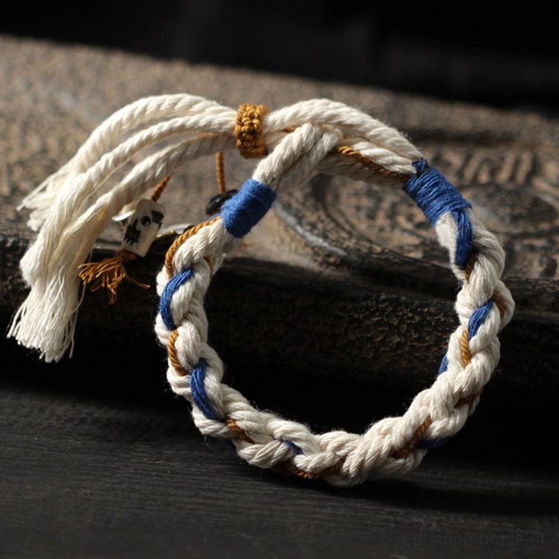 Tibetan Zakiram prosperity bracelet with tri-color braided design and fluffy tassels on dark wooden surface