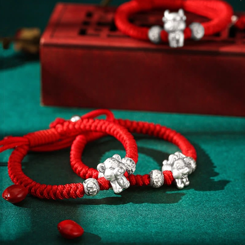 Collection of Chinese zodiac animal 999 sterling silver red braided rope bracelets oblique view with props