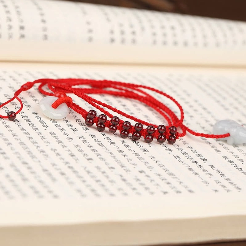 Chinese zodiac red string belly chain displayed on open ancient book pages