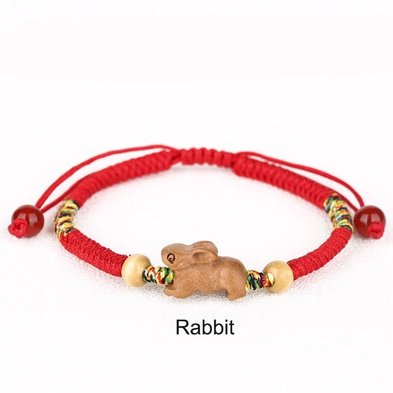 Zodiac animal red string bracelet top view white background