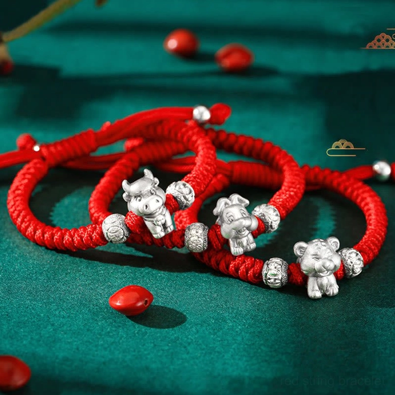 Multiple Chinese zodiac animal 999 sterling silver red rope bracelets collection top view with green background