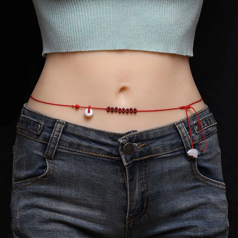 Chinese zodiac garnet red string belly chain worn on torso, showing braided rope with natural garnet beads and jade pendant