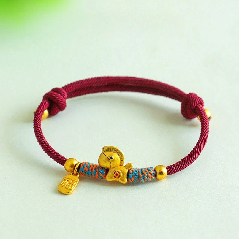 zodiac horse fu charm colorful woven red string bracelet flat lay on green background