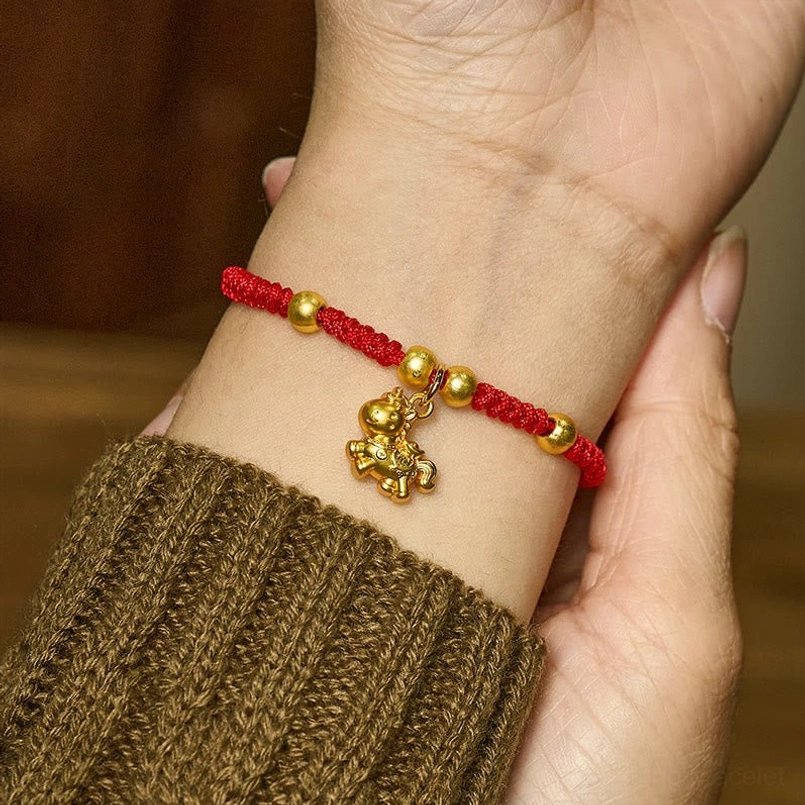 Red string horse charm bracelet worn on wrist with knitted sleeve, delicate 3D horse charm detail