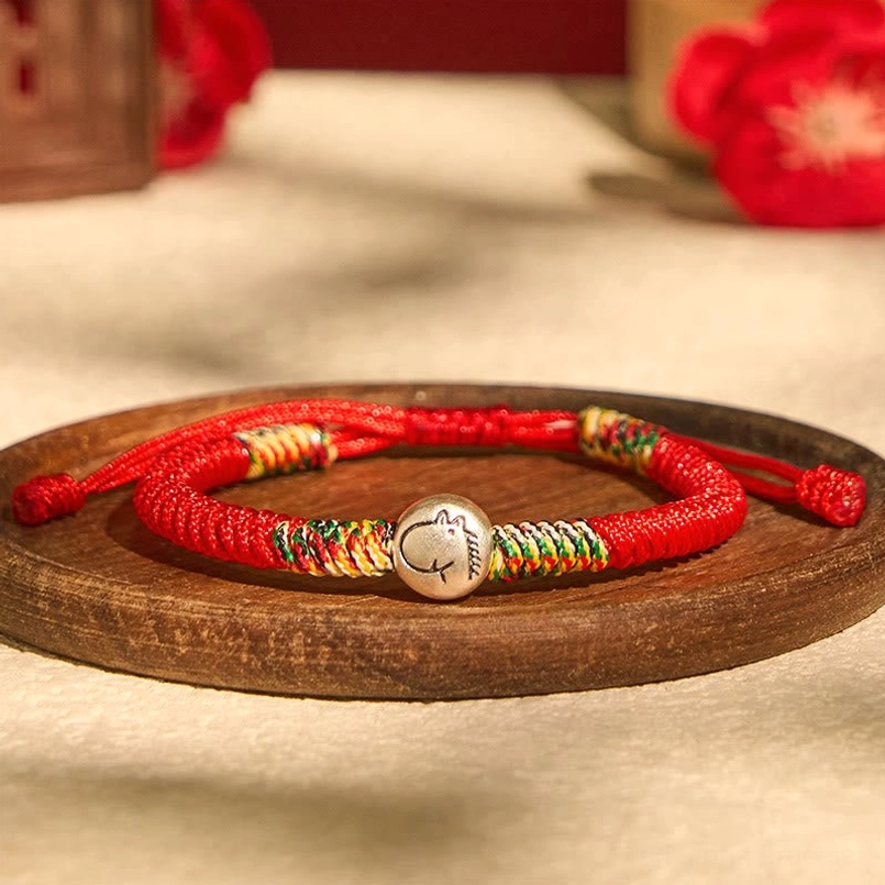 Two matching Zodiac Horse red string bracelets on wooden tray with floral decor