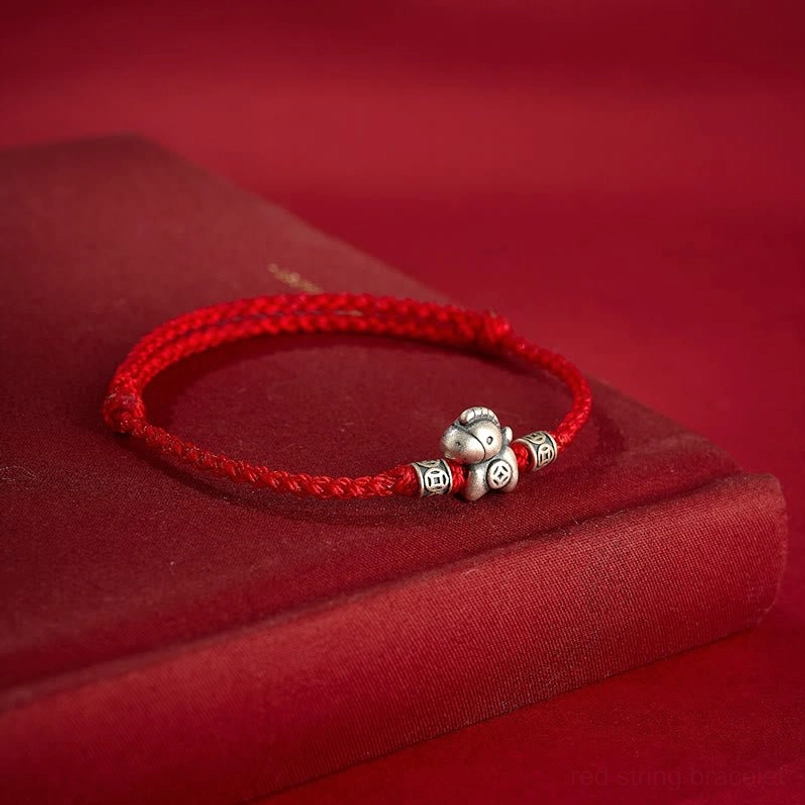 Zodiac horse red woven bracelet with silver horse and coin charms on maroon book