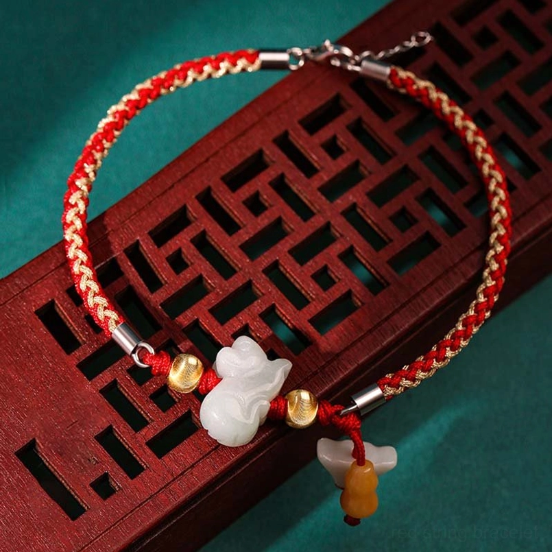 Single zodiac jade red string bracelet on wooden tray flat lay display