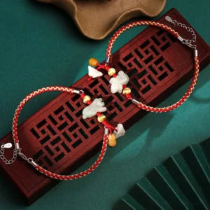 Chinese zodiac jade red string bracelet flat lay on wooden tray with gold beads