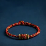 Handmade Chinese zodiac natal buddha red string bracelet with gold decorative knots on dark background