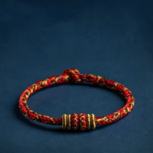 Handmade Chinese zodiac natal buddha red string bracelet with gold decorative knots on dark background