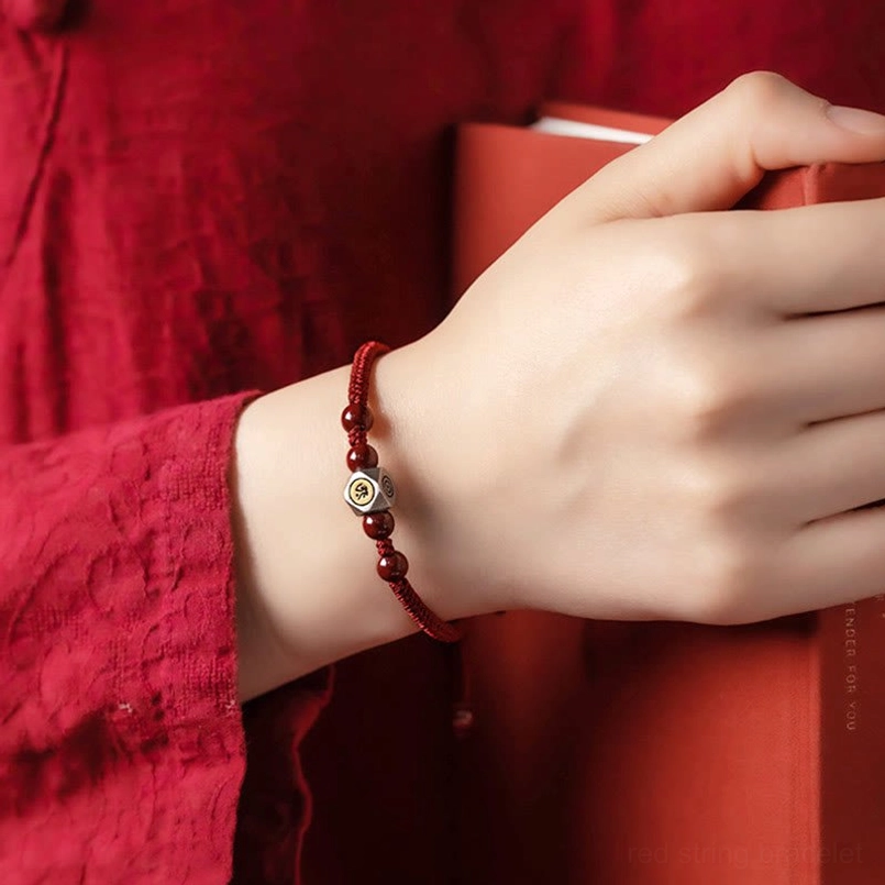 First-person view of worn zodiac natal buddha red string bracelet on wrist with casual daily outfit