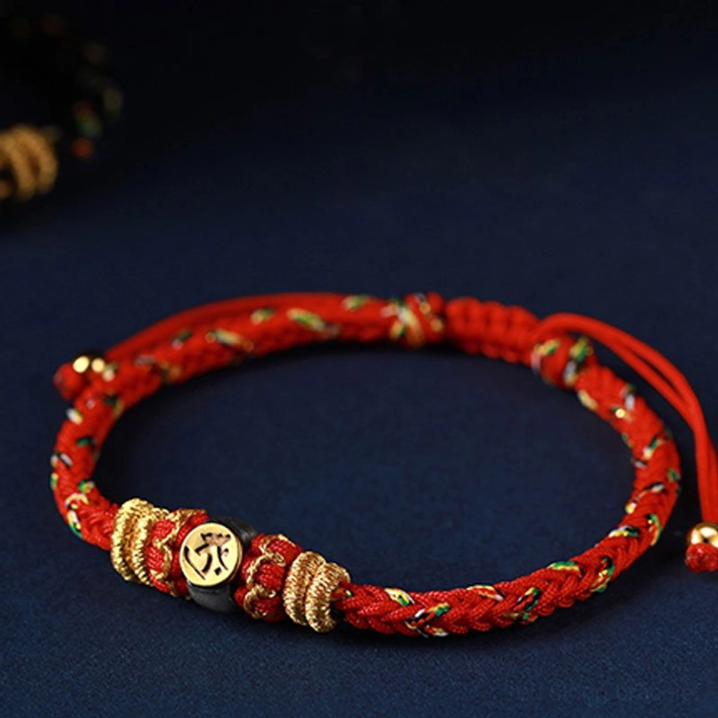 Bright red zodiac natal buddha bracelet with full circle top-down view displaying woven cord and engraved metal charm bead
