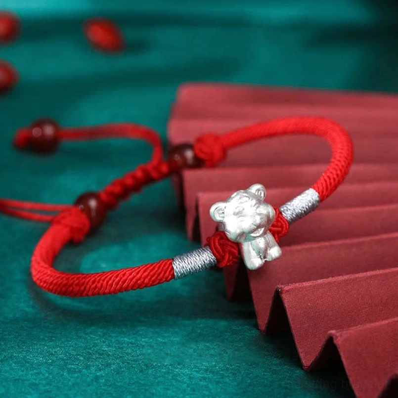 Single zodiac ox red string bracelet flat lay showing detailed sterling silver charm