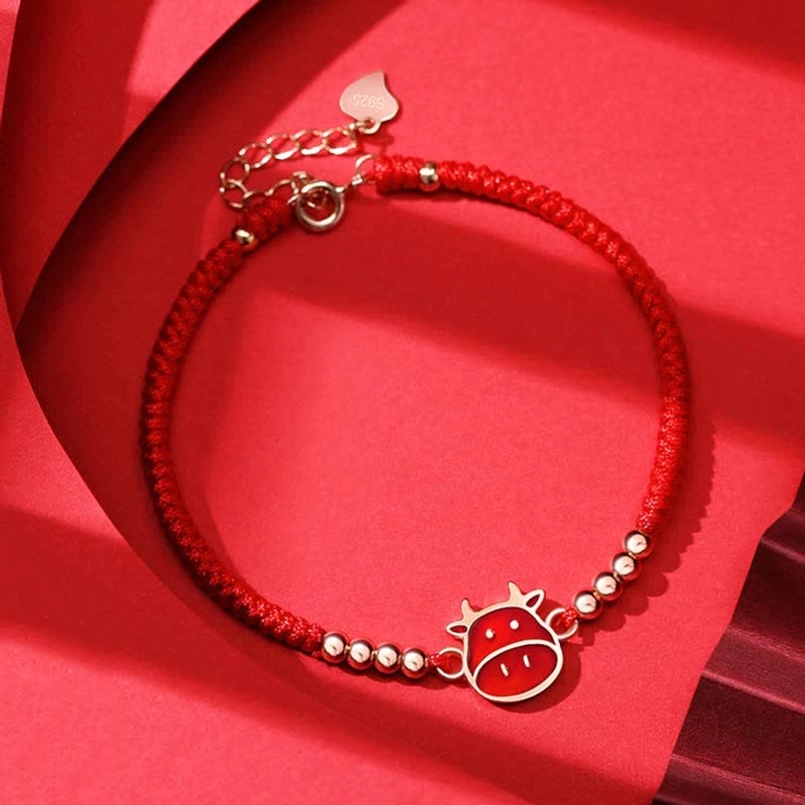 Chinese Zodiac Ox red string bracelet with enamel charm and sterling silver beads on red background