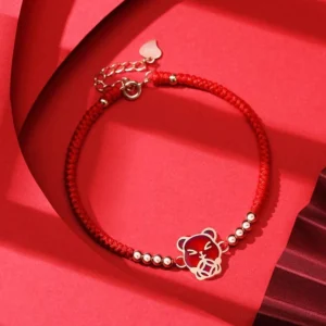 Chinese zodiac pig red string bracelet with rose gold charm on red fabric