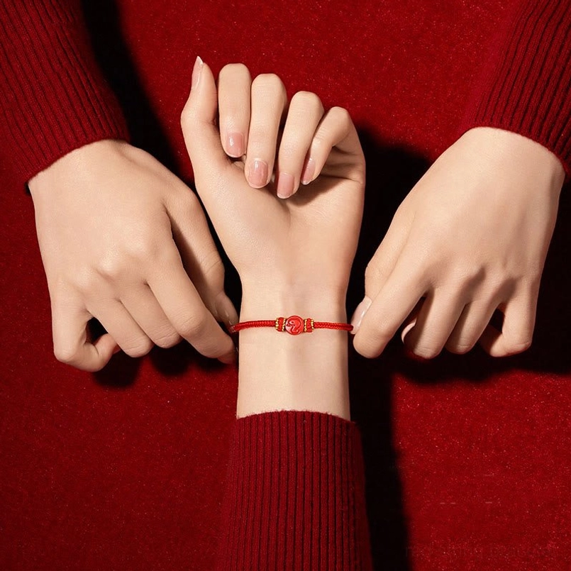 Worn Chinese zodiac red string bracelet on wrist with red sweater lifestyle photo