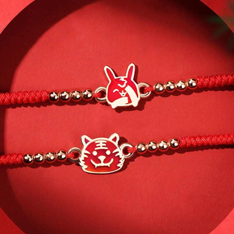 Two Chinese Zodiac red string bracelets with enamel animal charms on red circular background