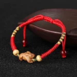 Chinese zodiac red string peach wood bracelet side view on wooden surface