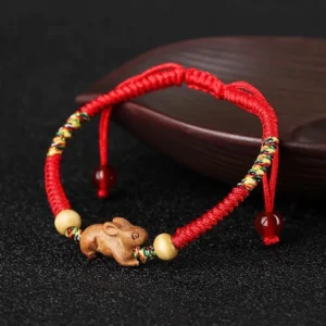 Chinese zodiac red string peach wood bracelet side view on wooden surface