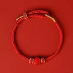 Chinese zodiac snake red string bracelet with eight thread peace knot and cinnabar charm, flat lay top view