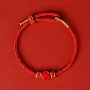 Chinese zodiac snake red string bracelet with eight thread peace knot and cinnabar charm, flat lay top view