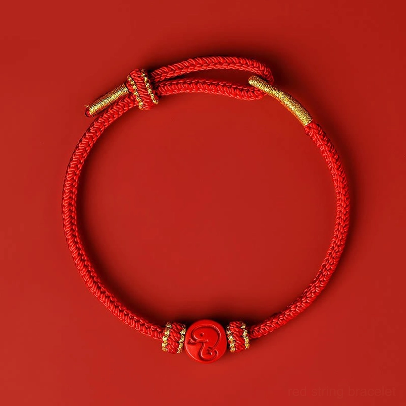 Chinese zodiac snake red string bracelet with eight thread peace knot and cinnabar charm, flat lay top view